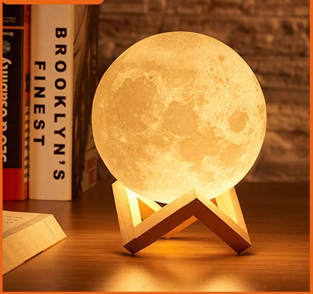 3D moon night light on its wooden stand beside books